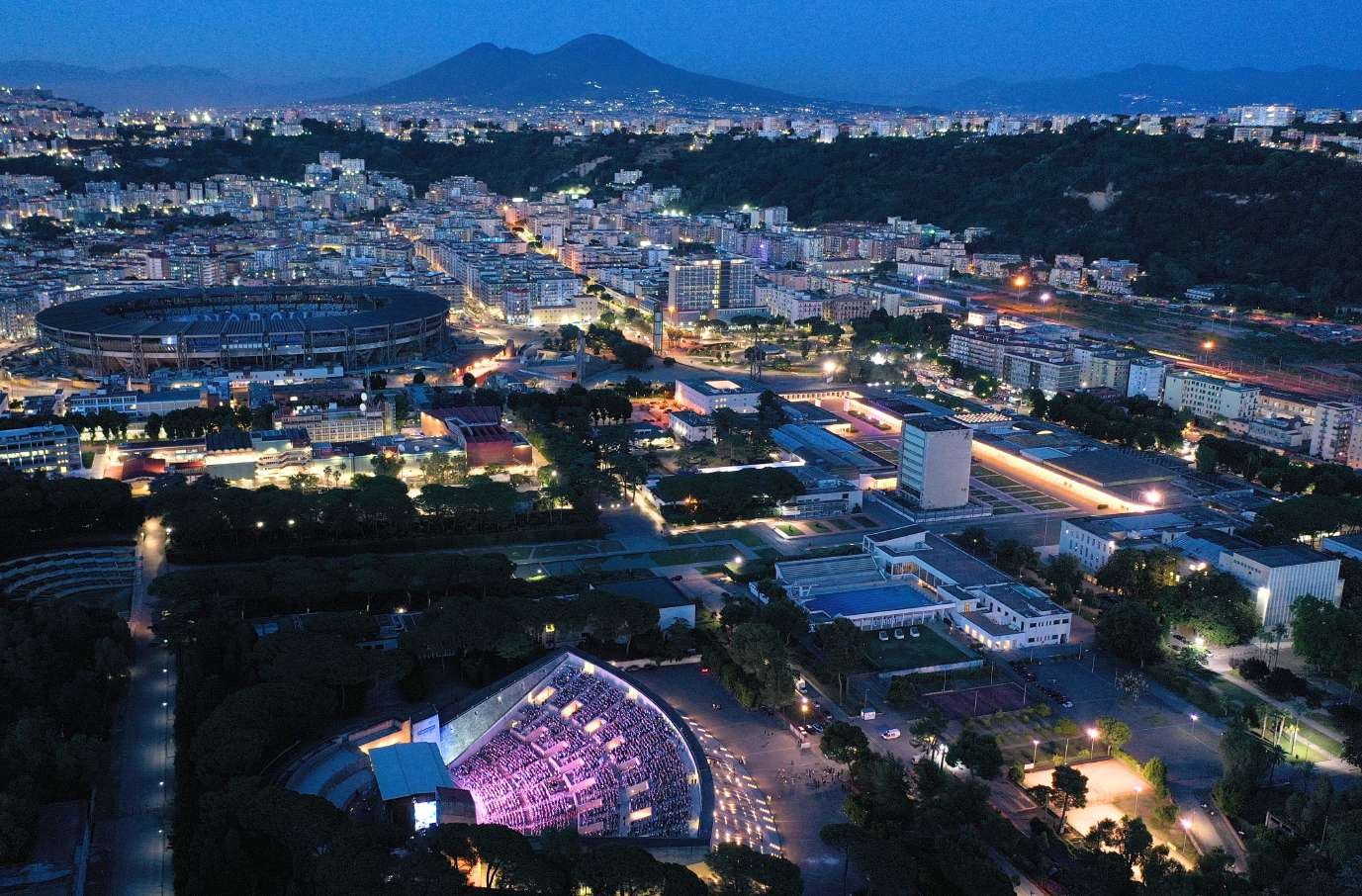 L'Arena Flegrea illuminata al crepuscolo, con lo stadio e il Vesuvio sullo sfondo